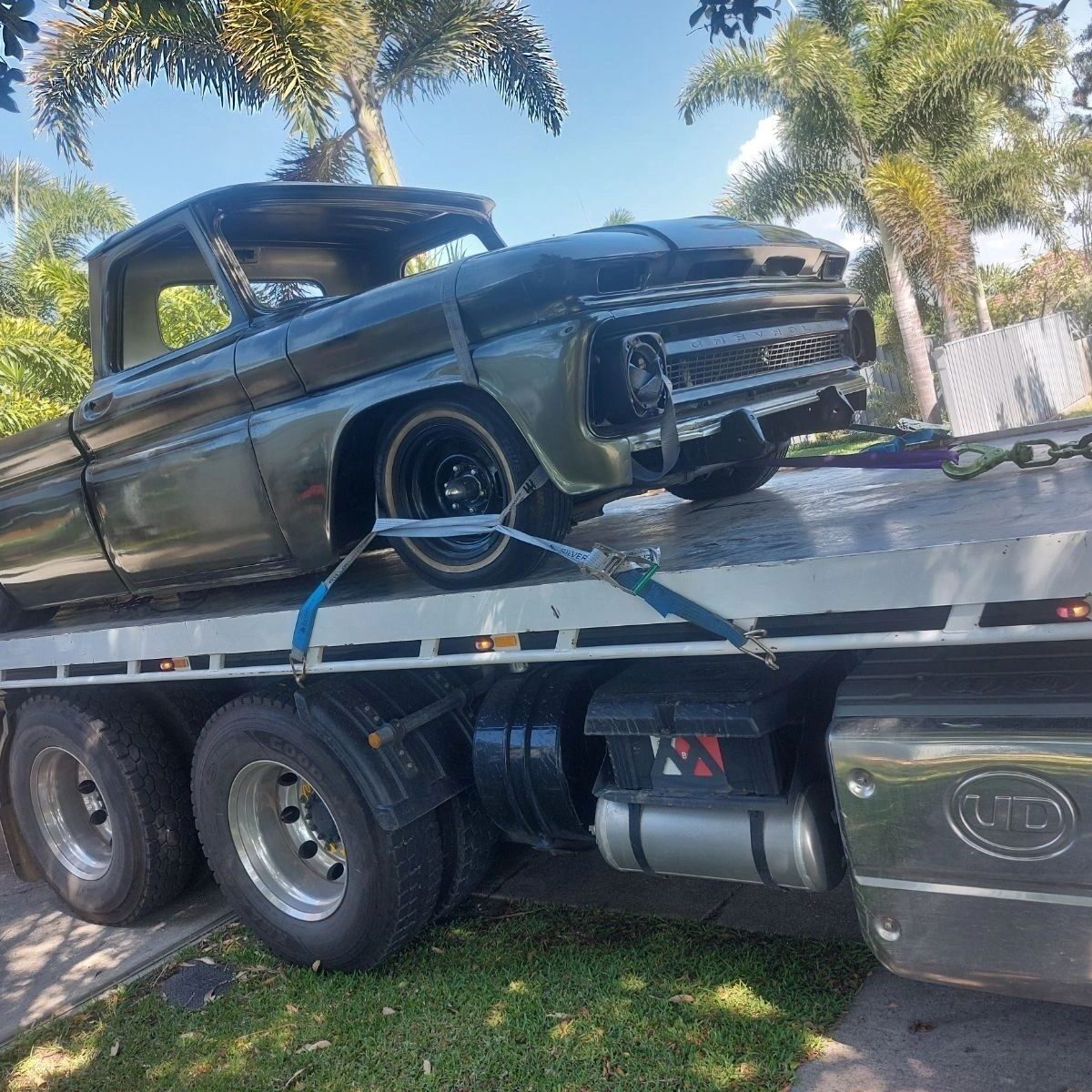 Flatbed truck transporting an old pickup truck.